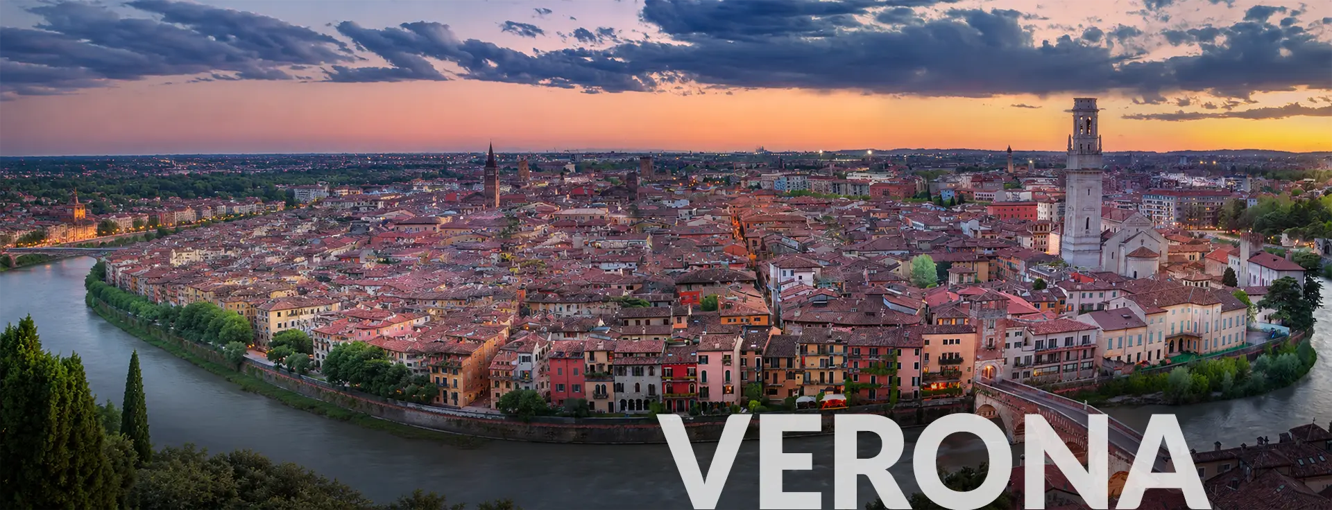 Panoramic view of Verona, Italy skyline at sunset with the Adige River and historic city center.