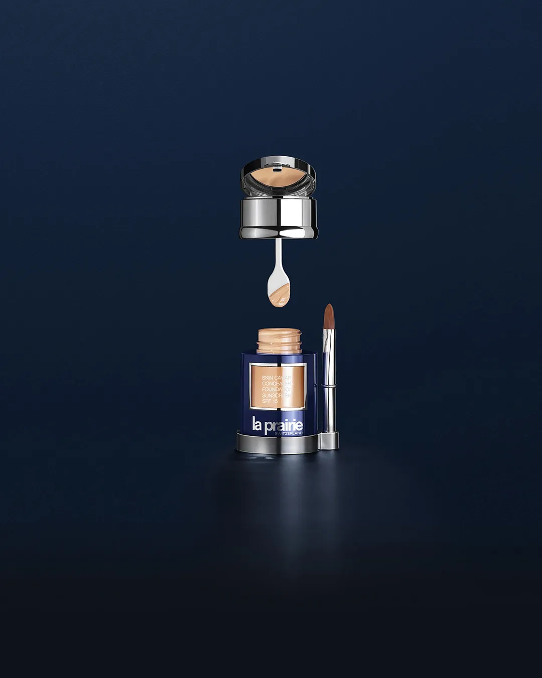 La Prairie Skin Caviar concealer foundation with brush and applicator on blue background